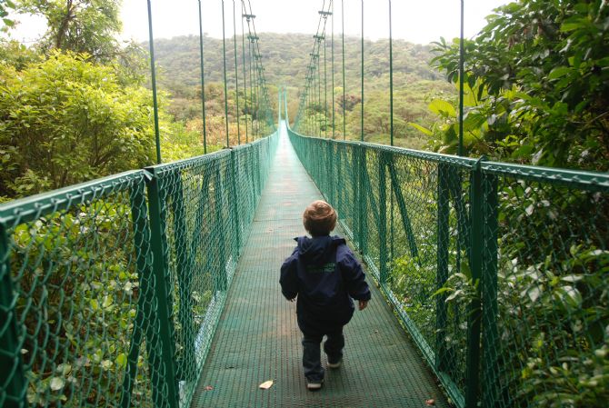 Niño preguntandose que habra del otro lado del puente, en el Parque Selvatura